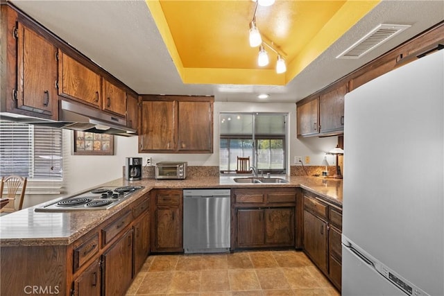 kitchen with visible vents, stainless steel appliances, a raised ceiling, under cabinet range hood, and a sink