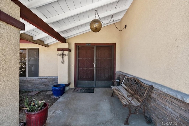 doorway to property featuring stone siding and stucco siding