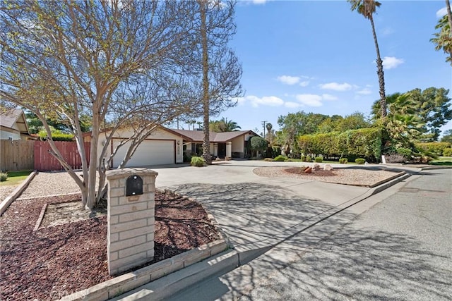 ranch-style house with curved driveway, a garage, and fence