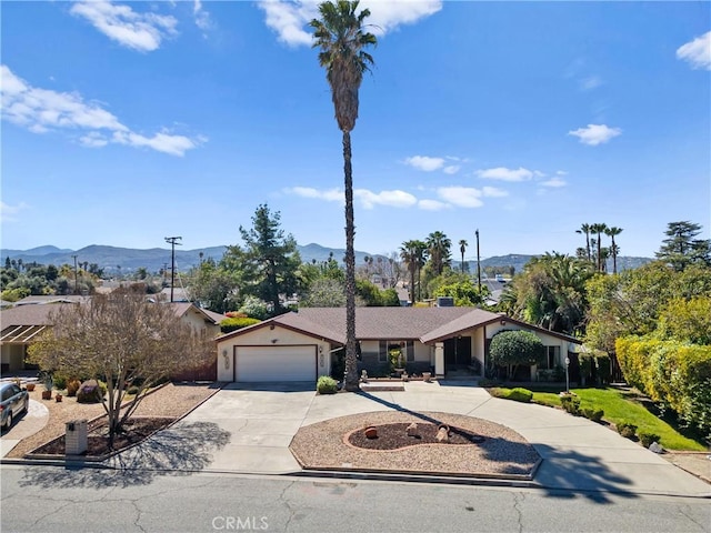 view of front of property with stucco siding, driveway, a mountain view, and an attached garage