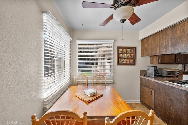 dining area with baseboards, ceiling fan, and a toaster