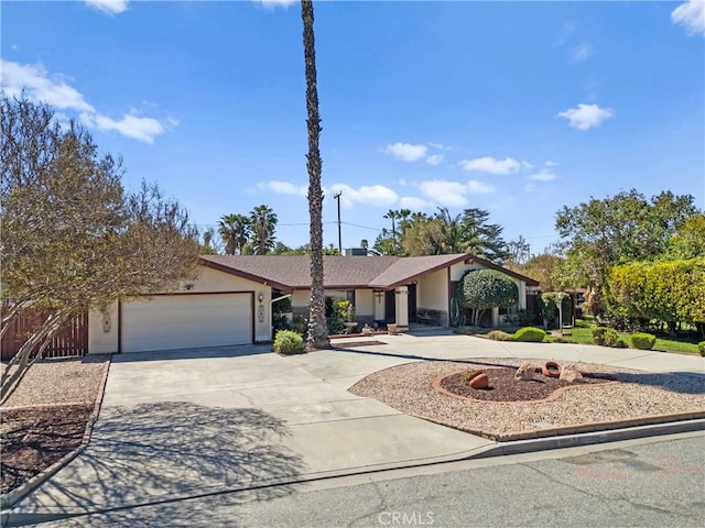 view of front of house with stucco siding, a garage, and curved driveway