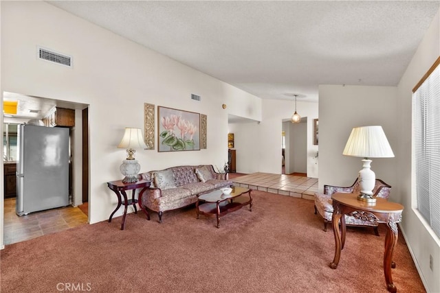living area with lofted ceiling, a textured ceiling, visible vents, and carpet