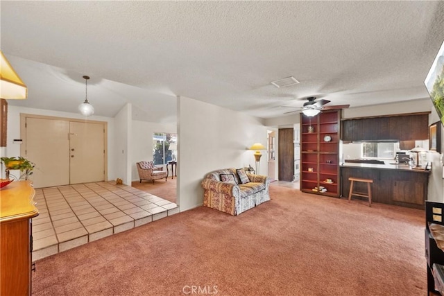 carpeted living room with a textured ceiling, lofted ceiling, ceiling fan, and visible vents