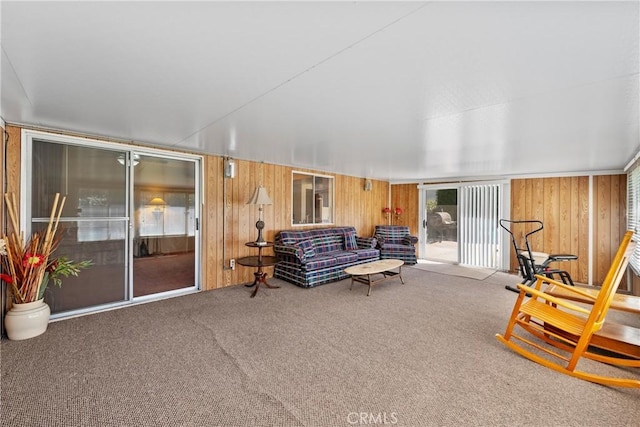 carpeted living room featuring wooden walls