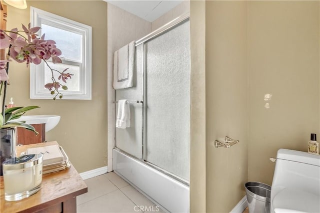 full bathroom with toilet, tile patterned floors, enclosed tub / shower combo, and baseboards