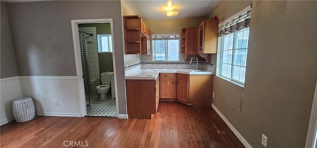 kitchen featuring baseboards, open shelves, a sink, dark wood-style floors, and brown cabinetry
