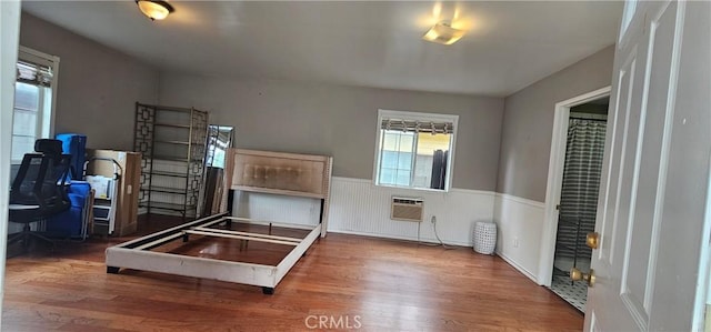 interior space with wainscoting, an AC wall unit, and wood finished floors