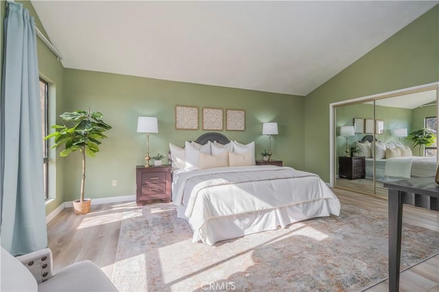 bedroom with baseboards, vaulted ceiling, wood finished floors, and a closet