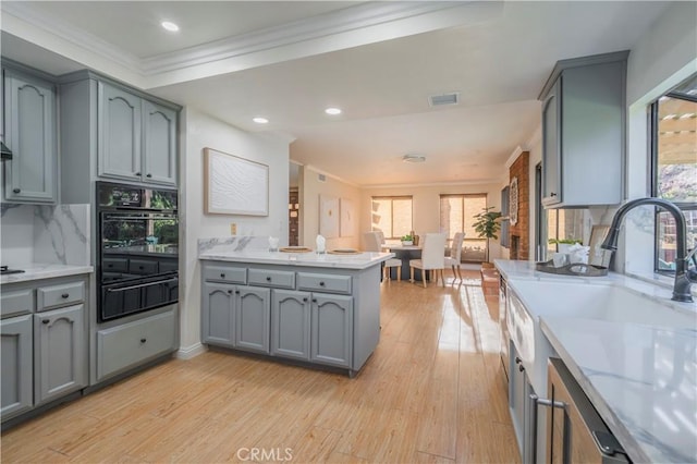 kitchen featuring a warming drawer, ornamental molding, gray cabinets, and oven