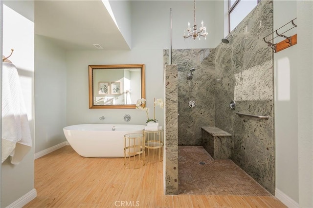 bathroom with baseboards, an inviting chandelier, a freestanding tub, wood finished floors, and a walk in shower