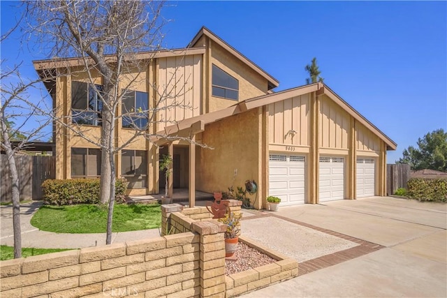 view of front facade featuring stucco siding, fence, concrete driveway, and a garage