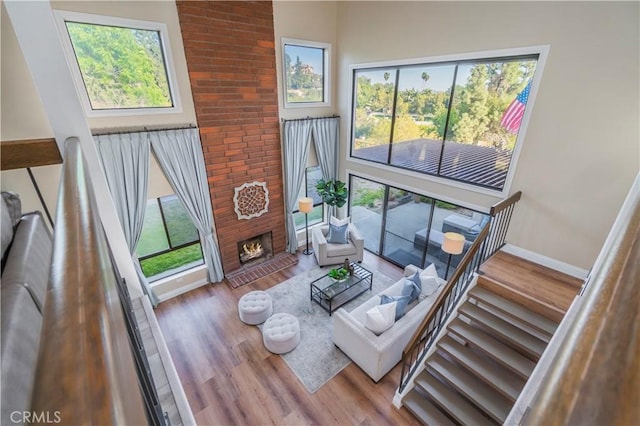 living area featuring a fireplace, wood finished floors, stairs, and baseboards