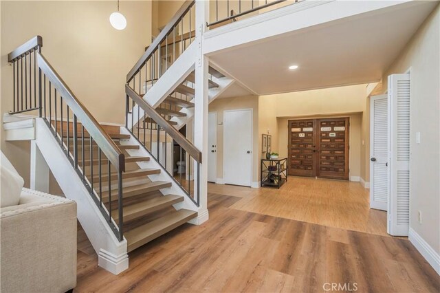 stairs with recessed lighting, wood finished floors, and baseboards
