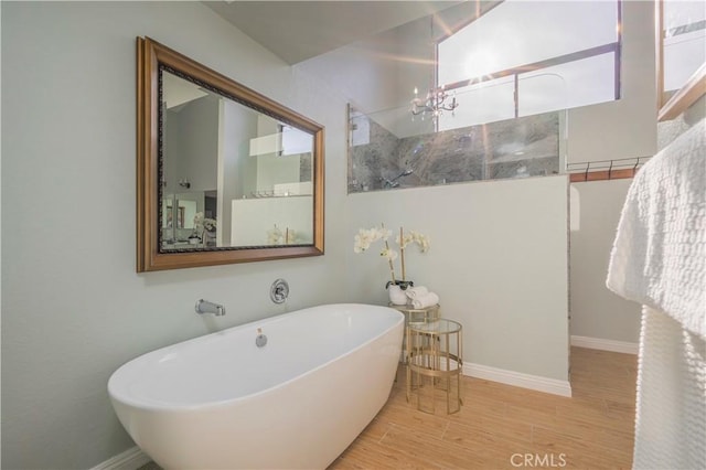 bathroom with a soaking tub, baseboards, and wood finished floors