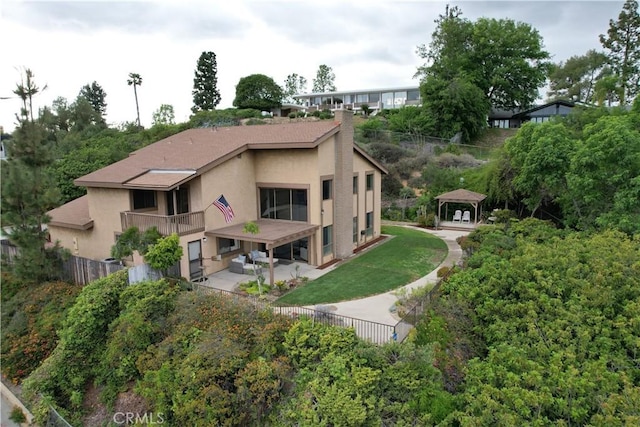 back of property with fence, a gazebo, and stucco siding