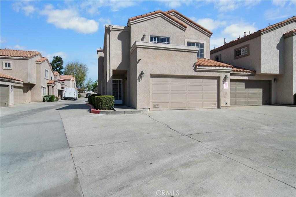 view of front of property with stucco siding, a tile roof, concrete driveway, and an attached garage