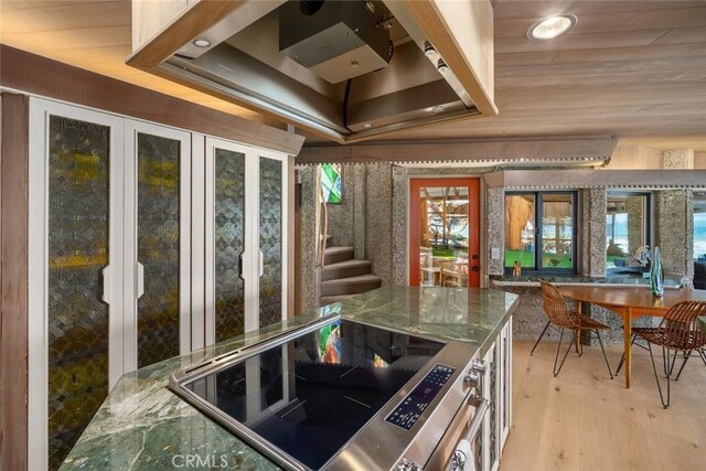 2431 Sherwood Dr, Cambria, CA 93428 - kitchen featuring light wood finished floors, dark stone countertops, range with electric cooktop, and a raised ceiling