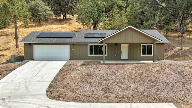 43179 E Sugar Pine Dr, Oakhurst, CA 93644 - ranch-style house with an attached garage, concrete driveway, solar panels, roof with shingles, and covered porch