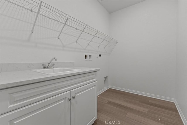 clothes washing area with electric dryer hookup, washer hookup, a sink, dark wood-style flooring, and cabinet space