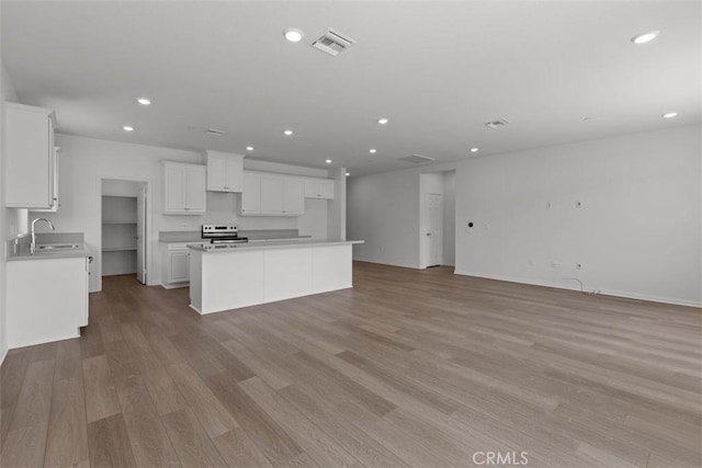 kitchen with recessed lighting, light wood-style flooring, white cabinetry, and electric stove