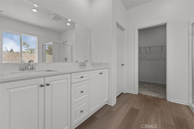 full bathroom featuring a sink, a shower stall, double vanity, and wood finished floors