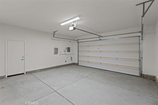 garage featuring a garage door opener, baseboards, and electric panel