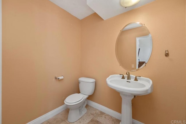 half bath with baseboards, tile patterned flooring, and toilet