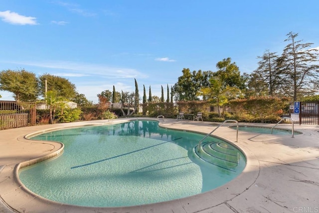 community pool with a patio area and fence