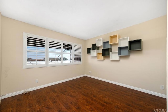 empty room featuring baseboards and dark wood-type flooring