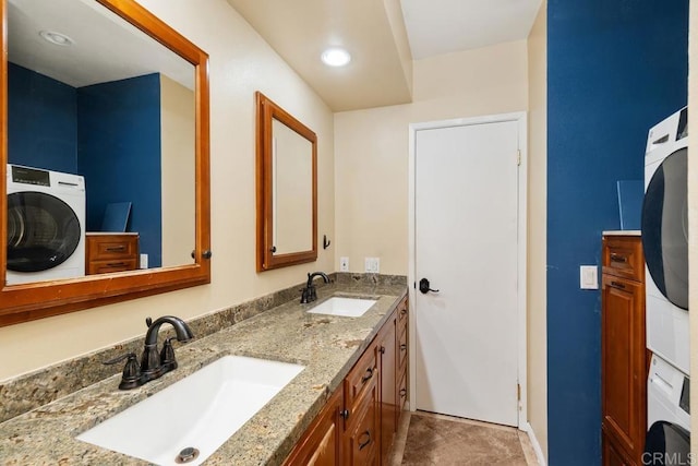 full bathroom featuring baseboards, a sink, stacked washer / drying machine, and double vanity