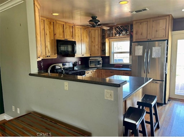 kitchen with stainless steel appliances, a peninsula, a breakfast bar area, and plenty of natural light