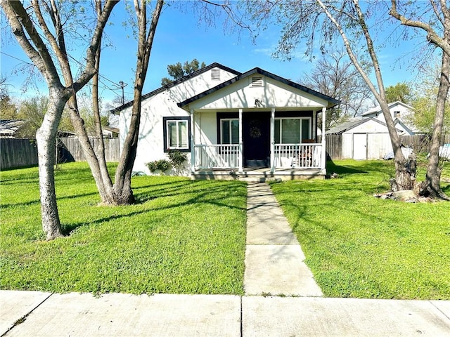 view of front of home with a shed, a front lawn, covered porch, and fence