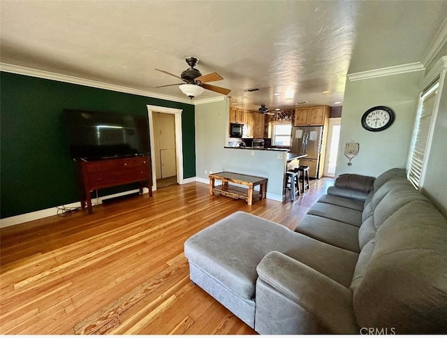 living area featuring crown molding, light wood-type flooring, a ceiling fan, and baseboards