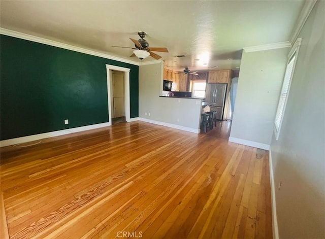 unfurnished living room featuring ornamental molding, wood-type flooring, baseboards, and a ceiling fan