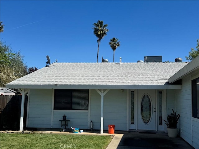 view of front facade featuring fence and roof with shingles
