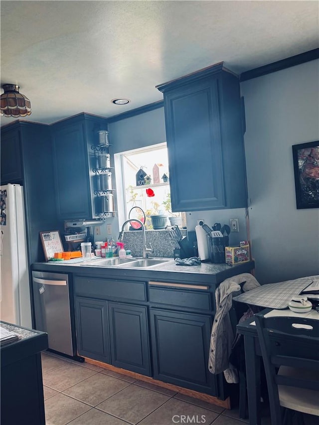 kitchen featuring a sink, freestanding refrigerator, blue cabinetry, dishwasher, and light tile patterned floors