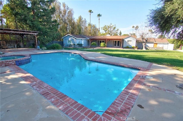 view of swimming pool with a lawn, a pool with connected hot tub, fence, and a patio
