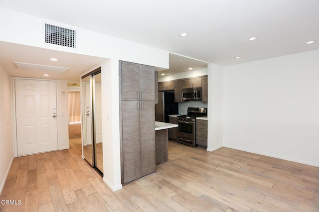kitchen featuring visible vents, baseboards, light wood-type flooring, light countertops, and appliances with stainless steel finishes
