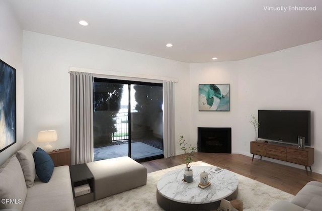 living room featuring a fireplace, recessed lighting, and wood finished floors
