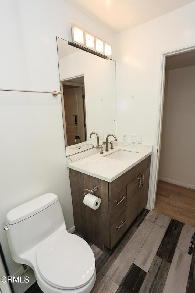 bathroom with vanity, wood finished floors, and toilet