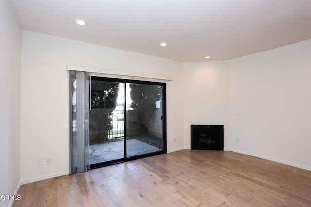 unfurnished living room with baseboards, wood finished floors, and a fireplace