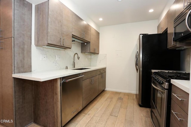 kitchen with backsplash, light wood-type flooring, a sink, stainless steel appliances, and recessed lighting