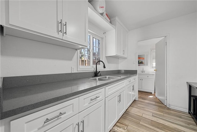 178 E 49th St, Los Angeles, CA 90011 - kitchen featuring light wood-style flooring, white cabinetry, a sink, and dark stone countertops