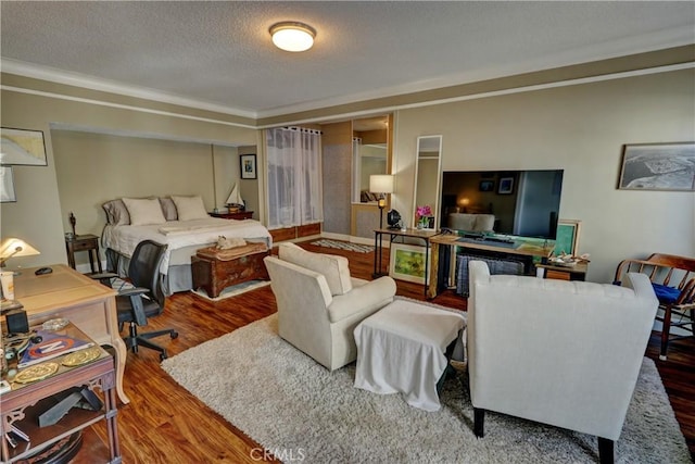 bedroom with crown molding, a textured ceiling, and wood finished floors