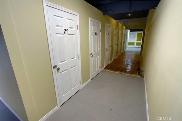 hall with baseboards and concrete floors
