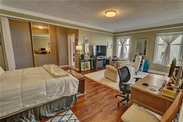 bedroom with crown molding, a textured ceiling, and wood finished floors