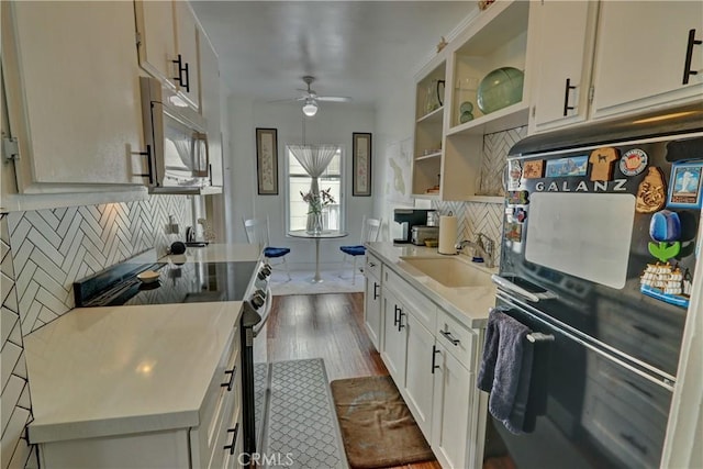 kitchen with a ceiling fan, black refrigerator, a sink, electric stove, and dark wood-style floors