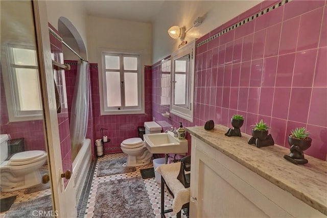full bath featuring tile walls, toilet, and a sink
