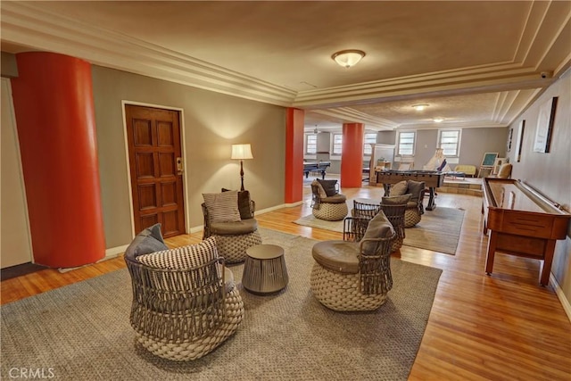 living area with light wood-type flooring, baseboards, and ornamental molding